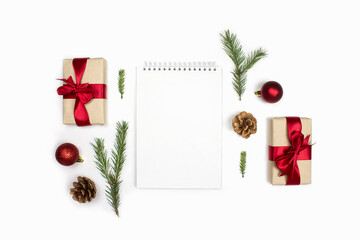 Fototapeta na wymiar Notebook, fir cones, spruce branches, red decorations, gifts flat lay isolated on white background, copy space. Christmas to do list, goals, wishes, shopping list, planning. New year, xmas celebration