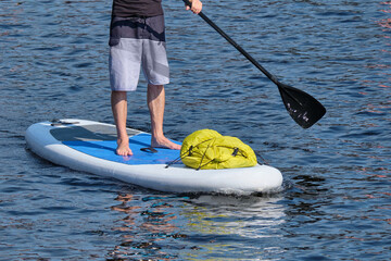 Person swims on sup surfing while standing on the board