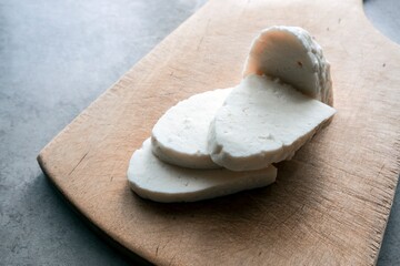 Adyghe cheese cut into pieces on a vintage wooden Board.