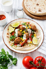 Tortilla with grilled meatball, corn and fresh salad.	