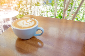 Coffee cup with heart shape latte art on wooden table at cafe. Copy space.