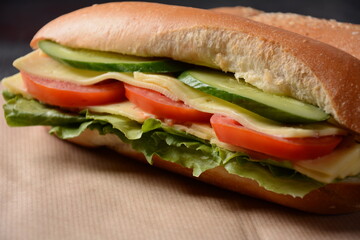 Sandwiches with cheese, lettuce, tomatoes and cucumber on a on a dark background