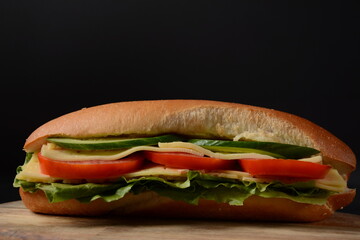 Sandwiches with cheese, lettuce, tomatoes and cucumber on a on a dark background