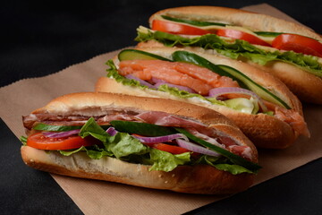Baguette sub sandwiches with salmon fish, bacon, cheese, onions, cucumbers, lettuce