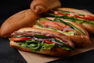 Baguette sub sandwiches with salmon fish, bacon, cheese, onions, cucumbers, lettuce