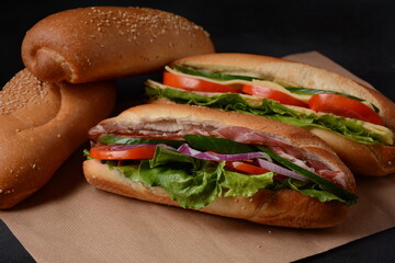 Baguette sub sandwiches with salmon fish, bacon, cheese, onions, cucumbers, lettuce