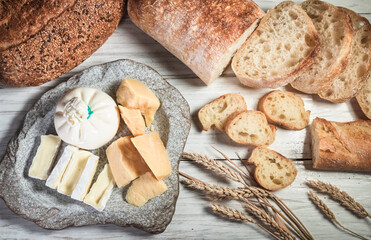 Sliced rustic bread and cheese on a white wooden board. Healthy food and farming concept
