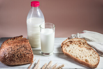 A glass of milk, sliced rustic bread and jam, on a white wooden board. Healthy food and farming concept