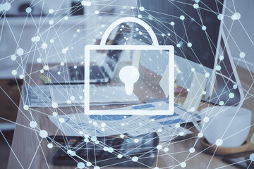 Double exposure of desktop with computer and lock icon hologram. Concept of data safety.