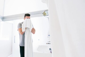 a man wipes himself with a white towel after washing his face