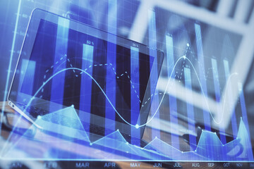 Stock market graph on background with desk and personal computer. Multi exposure. Concept of financial analysis.