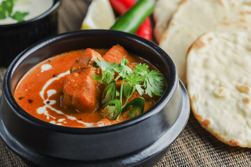 Butter chicken bowl and naan bread on wooden table. Curry - Meal, Indian food.