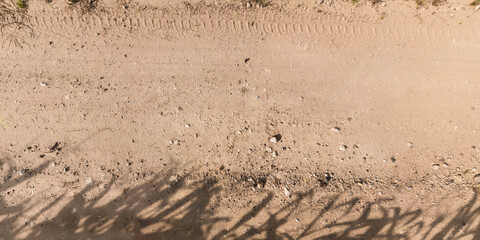 view from above on surface of gravel road with car tire tracks