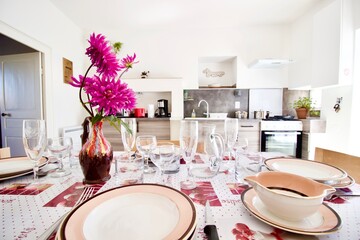Dinner table set and ready to eat, with a vase of pink flowers