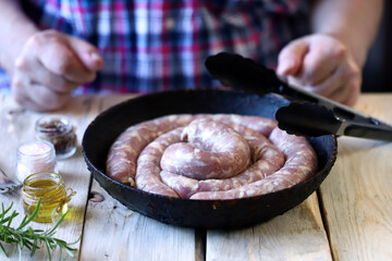 The chef puts raw sausages in a skillet. Cooking Bavarian sausages. Selective focus.