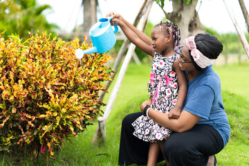 African American cute girl water the plants outdoors at home.