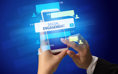 Female hand typing on smartphone with SOCIAL ENGAGEMENT inscription, social networking concept
