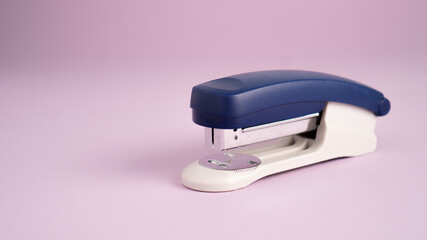 Blue stapler isolated on a purple background. Office supplies. Stapler, staple, paper, cardboard, office equipment