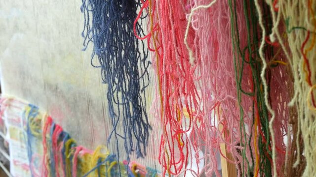 A large number of different woolen threads. Handmade carpet embroidery. Women's hands create a pattern using multi-colored threads. Hammer for embroidery quors, stuffing threads.