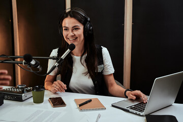 Portait of attractive young female radio host speaking in microphone while moderating a live show