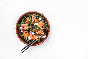 Gourmet salad with blue cheese, peaches, jamon ham and arugula on a light background, Flat lay. Banner. Top view