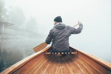 Man paddling canoe on the misty lake