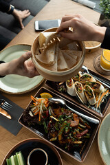 A woman takes pita bread, pita or Asian flatbreads from a man's hands as a Peking duck snack. Dinner for two at the restaurant. Pan-Asian oriental cuisine.
