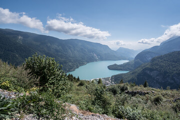 Obraz premium Molveno Lake, located in Trentino, by Molveno village, surrounded by Brenta group in the west & Gazza & Pagenella mountains in the south & east, as seen from Pradel high plain, Dolomites, Italy
