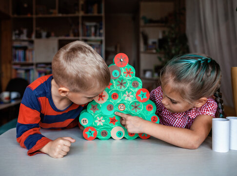 Kids making handmade advent calendar with toilet paper rolls at home. Seasonal activity for kids