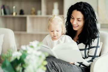 an interesting fairy tale with a happy ending. Flowers in the foreground. a brunette woman of European appearance reads a new book to her little daughter baby kids.