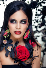 pretty brunette woman with rose jewelry, black and red, bright make up a vampire closeup red lips