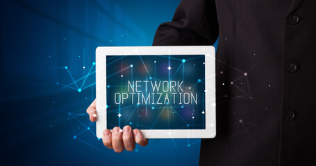 Young business person working on tablet and shows the digital sign: NETWORK OPTIMIZATION