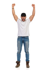 Confident Young Man Is Standing With Arms Raised And Shouting