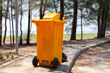 Yellow garbage bins in the park near the sea.