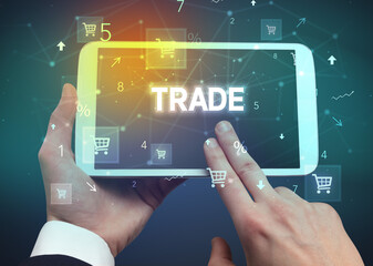 Close-up of a hand holding tablet with TRADE inscription, online shopping concept
