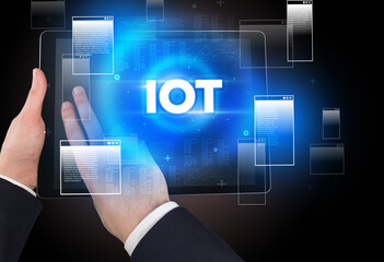 Close-up of a hand holding tablet with IOT abbreviation, modern technology concept