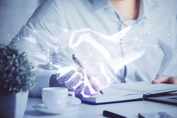 Abstract polygonal handshake on people hands writing background. Teamwork concept. Double exposure.