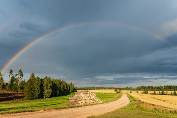 Rainbow over the road, forest and fields