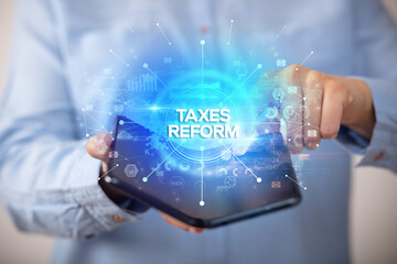 Businessman holding a foldable smartphone with TAXES REFORM inscription, new business concept