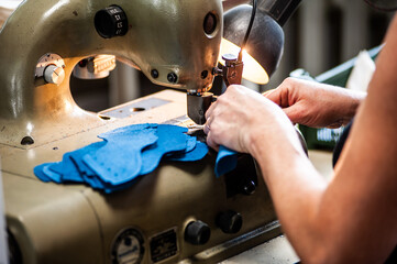 The master sews leather garments at the factory