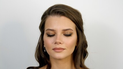 Fototapeta premium Portrait of a beautiful young woman with fresh skin. Pretty face with a grey eyes of an adult girl. Closed female eyes with make-up. Close-up. Attractive model looks down