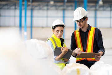 Obraz premium Female Inventory Manager checking stock on Digital Tablet. Man warehouse worker with hard hat safety helmet at storage buildings