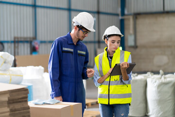 Female Inventory Manager checking stock on Digital Tablet. Man warehouse worker with hard hat safety helmet at storage buildings