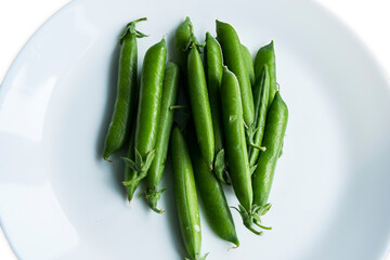 Pea pods in a plate on an isolated white background.