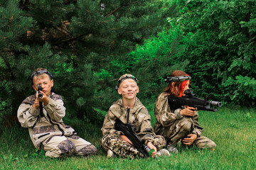 Children playing in lasertag shooting game in open air. Weapon in the hands of people. War simulation. Banner.	