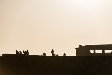 Fototapeta na wymiar Silhouette of tourists enjoying the sunset at the Ermida de la Lanzada hermitage in Sanxenxo, Galicia, Spain.