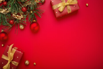 Red Christmas gifts, green fir tree, gold decorations on holiday background. Copy space, flat lay.