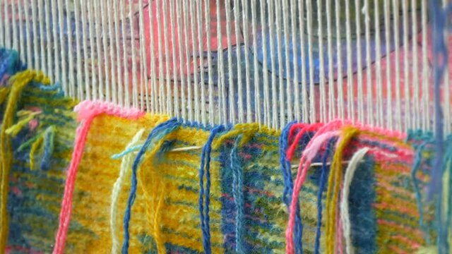 Handmade carpet embroidery. Women's hands create a pattern using multi-colored threads. Hammer for embroidery quors, stuffing threads. Close up view.