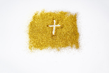 Drawing a cross on the golden sand glitter. A cross against a gold texture on the glitter background. A Shiny gold glitter on the background.