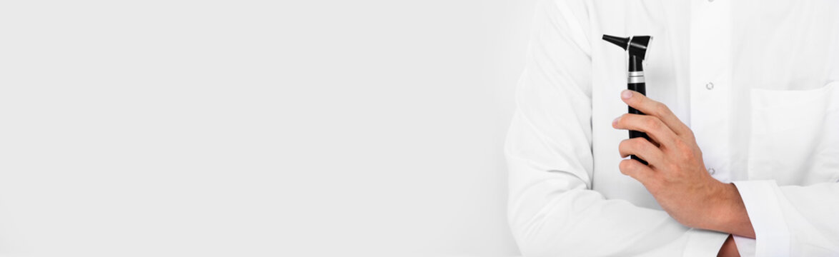 Web banner, an audiologist with otoscope on grey background. Ear treatment and hear exam